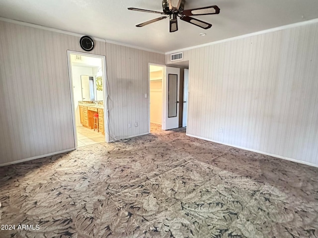 interior space featuring a spacious closet, ornamental molding, ensuite bath, and ceiling fan