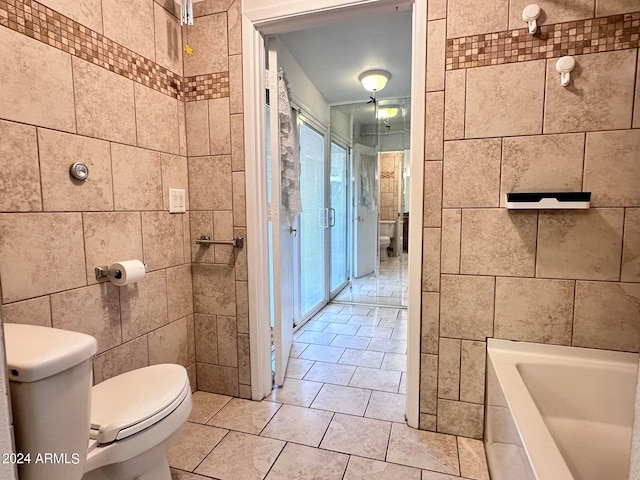 bathroom featuring tile walls, a bathtub, and toilet