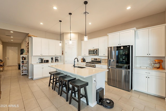 kitchen featuring appliances with stainless steel finishes, white cabinetry, sink, and a center island with sink