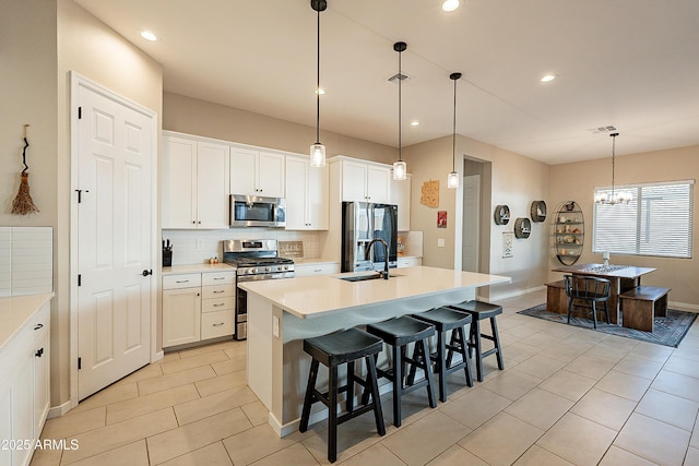 kitchen with appliances with stainless steel finishes, a breakfast bar, white cabinets, and a center island with sink