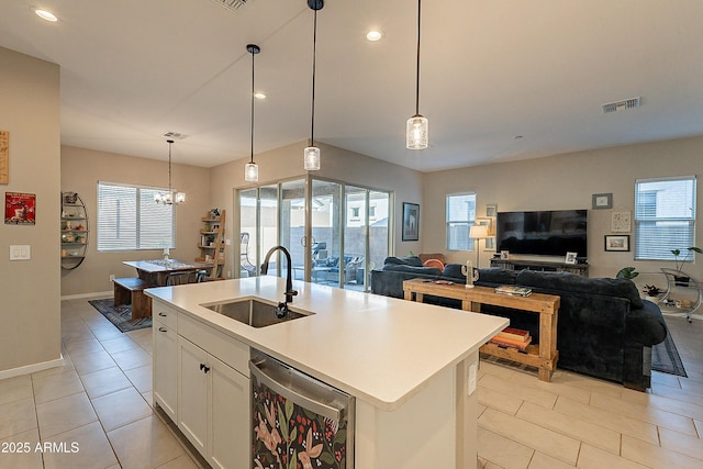 kitchen with sink, beverage cooler, decorative light fixtures, and a center island with sink