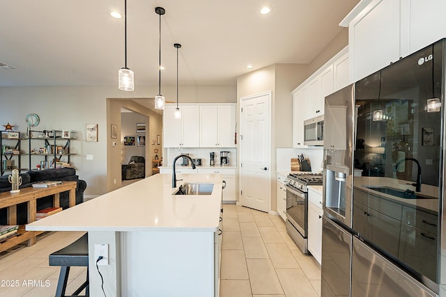 kitchen with sink, stainless steel appliances, white cabinetry, and a kitchen island with sink