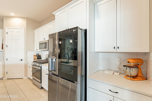 kitchen featuring stainless steel appliances, white cabinetry, light tile patterned floors, and decorative backsplash