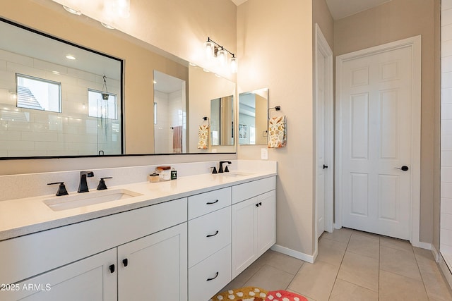 bathroom featuring tile patterned flooring, a tile shower, and vanity