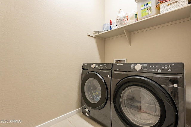 clothes washing area featuring washer and clothes dryer and light tile patterned floors