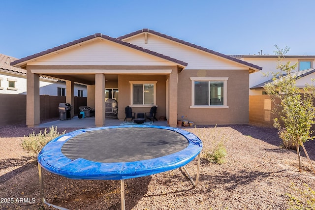 back of property featuring a patio area and a trampoline