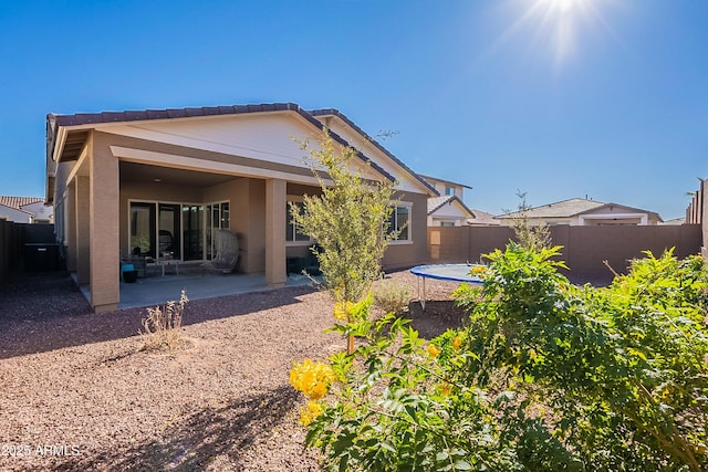 back of property featuring a trampoline and a patio