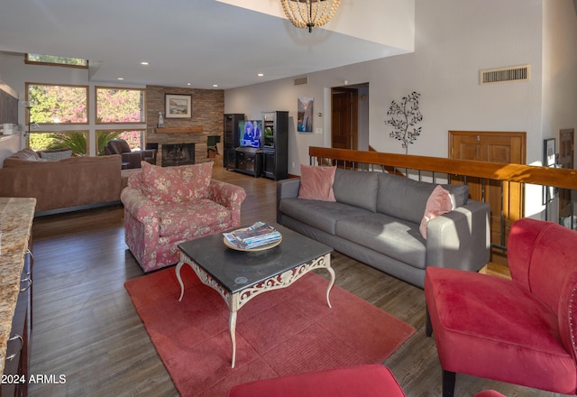 living room with dark wood-type flooring, an inviting chandelier, and a fireplace