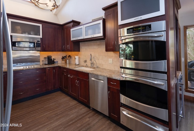 kitchen featuring stainless steel appliances, tasteful backsplash, dark hardwood / wood-style flooring, light stone countertops, and sink