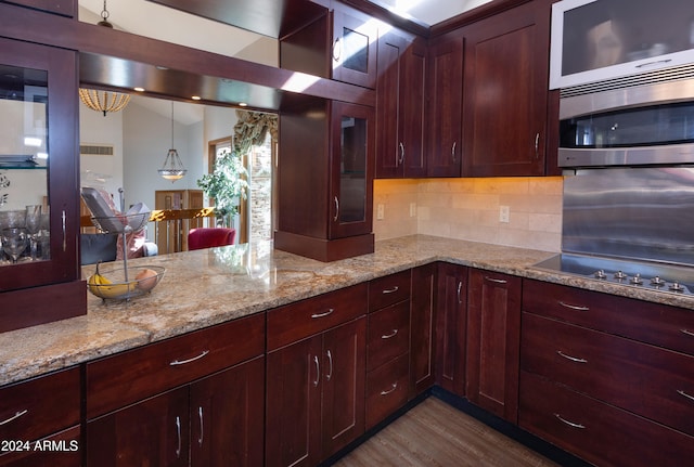 kitchen with decorative light fixtures, tasteful backsplash, light hardwood / wood-style flooring, light stone countertops, and gas stovetop