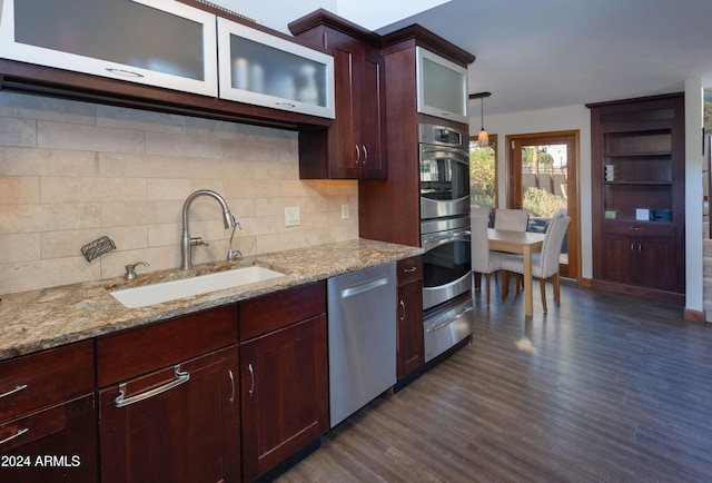 kitchen with decorative light fixtures, dark hardwood / wood-style floors, sink, light stone countertops, and appliances with stainless steel finishes