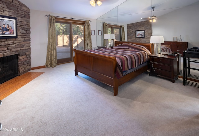 bedroom featuring vaulted ceiling, access to exterior, light colored carpet, and a stone fireplace