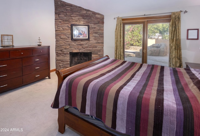 bedroom featuring light colored carpet, lofted ceiling, access to outside, and a stone fireplace