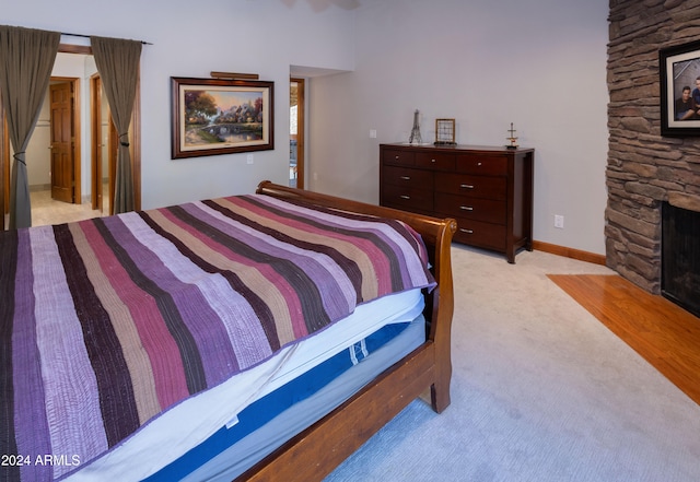 bedroom featuring light colored carpet, ensuite bath, and a stone fireplace