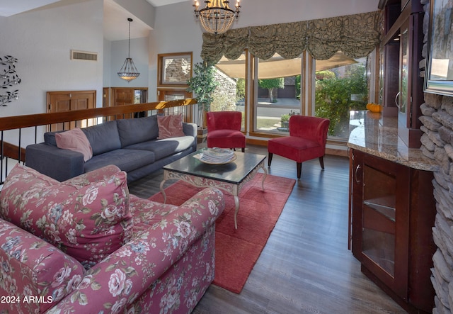 living room with lofted ceiling, dark hardwood / wood-style floors, and an inviting chandelier