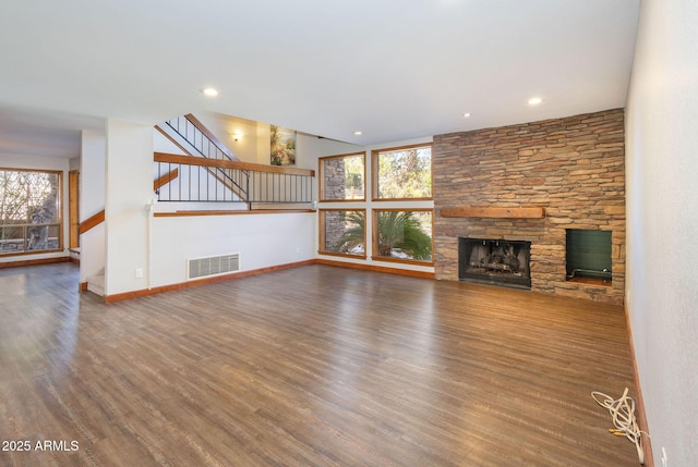 unfurnished living room featuring a wealth of natural light, a fireplace, and dark hardwood / wood-style floors