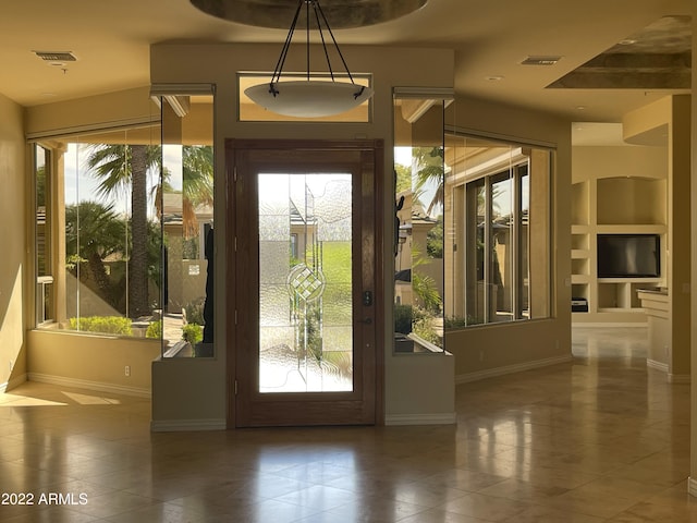 entryway with built in shelves, dark tile patterned floors, and plenty of natural light