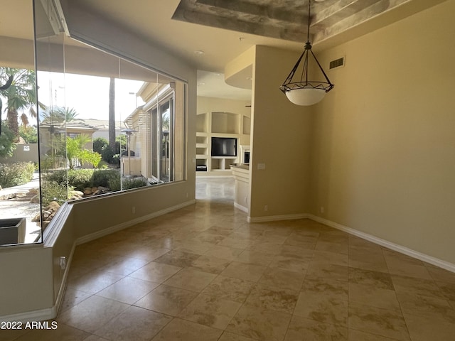 unfurnished dining area featuring a raised ceiling, built in features, and a fireplace