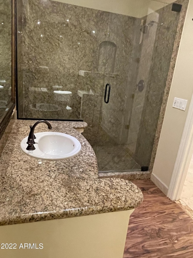 bathroom featuring walk in shower, vanity, and hardwood / wood-style flooring