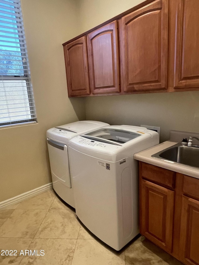 laundry area featuring light tile patterned flooring, cabinets, sink, and washing machine and dryer