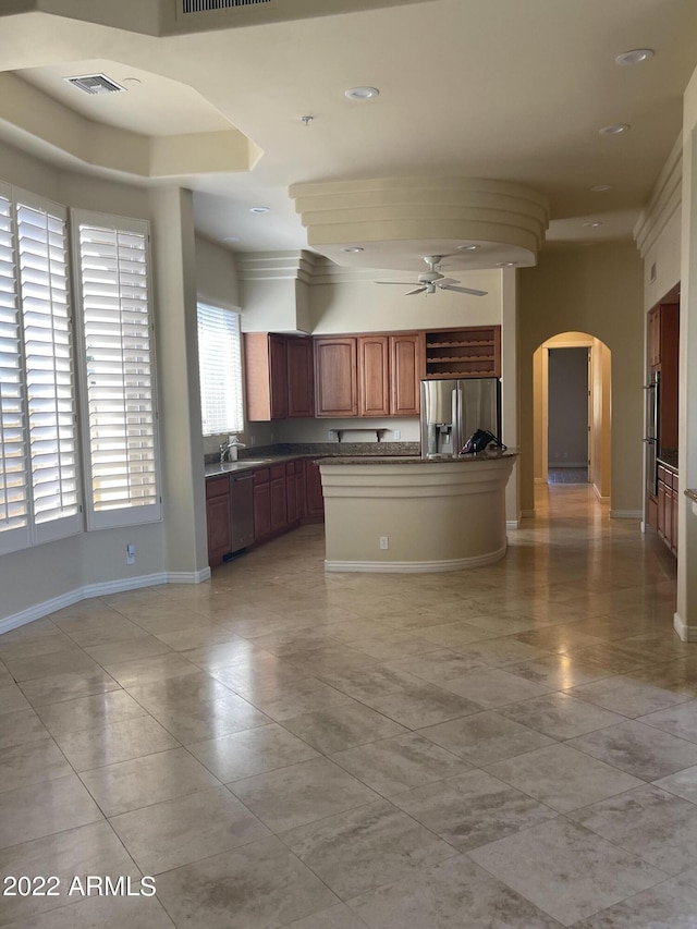 kitchen with ceiling fan, sink, stainless steel appliances, and an island with sink