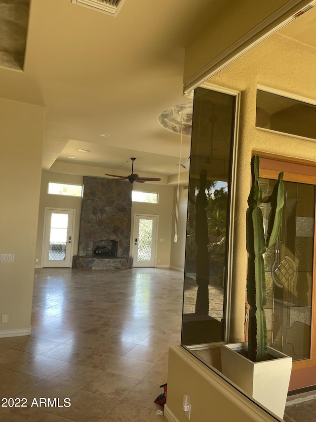 unfurnished living room with ceiling fan, a fireplace, and a tray ceiling