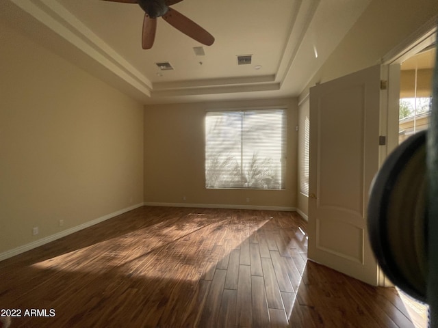spare room featuring a raised ceiling, ceiling fan, and dark hardwood / wood-style flooring