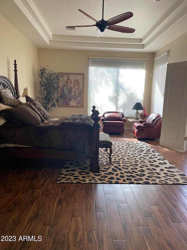 bedroom with hardwood / wood-style floors, a tray ceiling, and ceiling fan