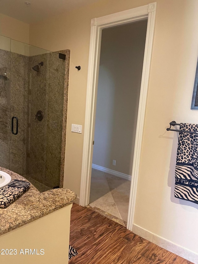 bathroom with wood-type flooring, vanity, and a shower with shower door