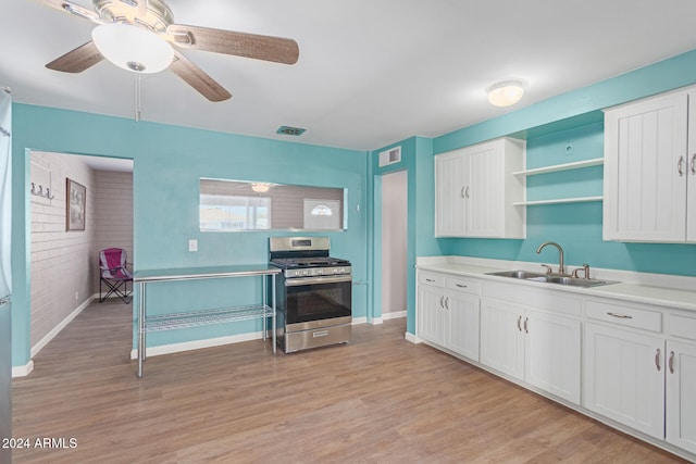 kitchen featuring gas range, light hardwood / wood-style flooring, white cabinets, and sink