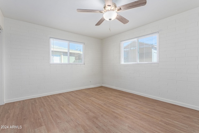 unfurnished room featuring light hardwood / wood-style floors, brick wall, and ceiling fan