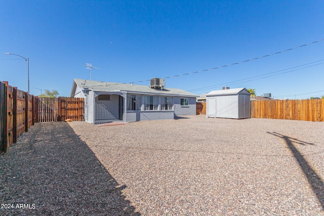 rear view of house with a storage shed and central AC unit