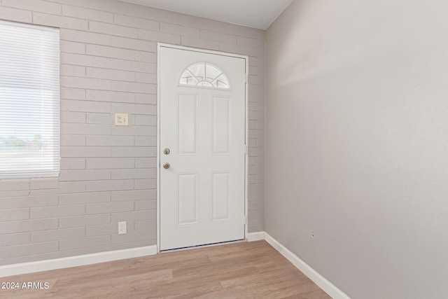 entryway with brick wall and light hardwood / wood-style floors