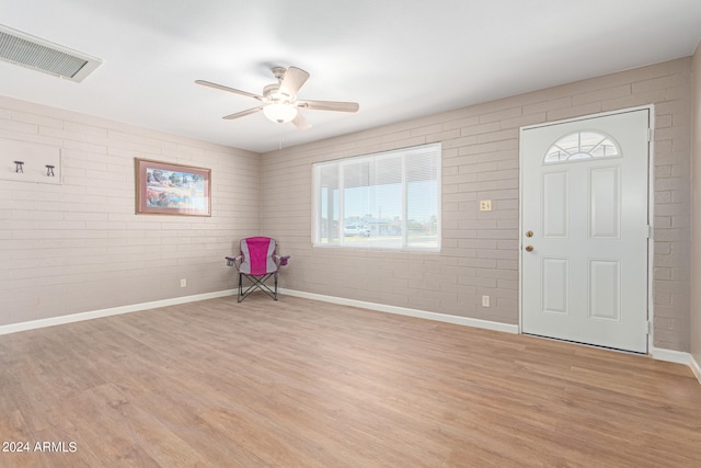 foyer with light hardwood / wood-style floors, brick wall, and ceiling fan