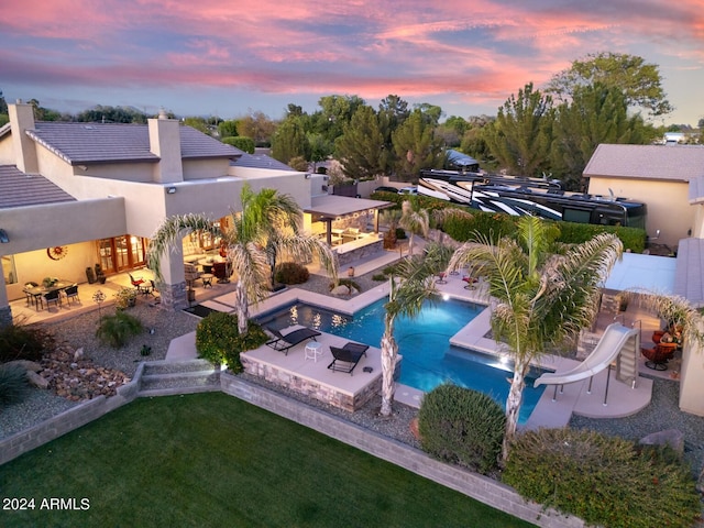 pool featuring a lawn, outdoor lounge area, a patio, a water slide, and outdoor dining space