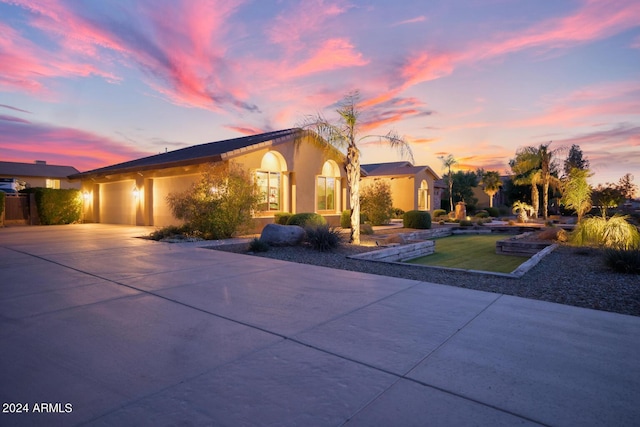 view of front of property with an attached garage, stucco siding, and concrete driveway