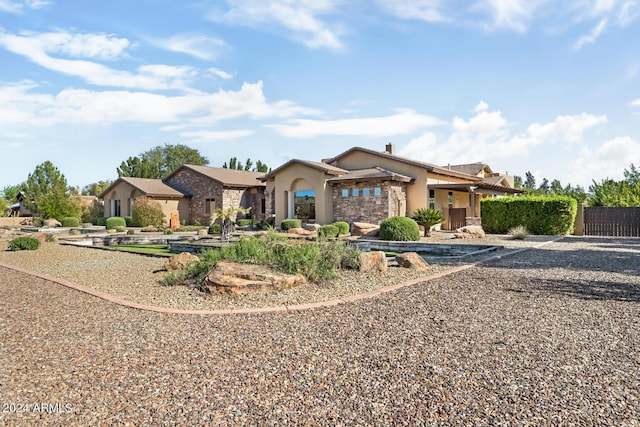 ranch-style home with fence, stone siding, and stucco siding