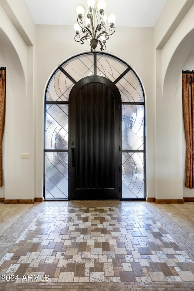 entryway featuring an inviting chandelier, baseboards, and arched walkways