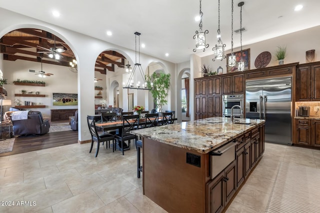kitchen featuring a sink, open floor plan, stainless steel built in fridge, arched walkways, and a warming drawer
