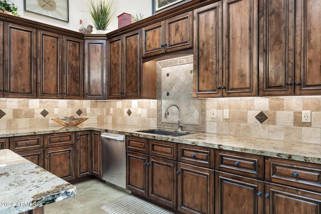 kitchen with light stone counters, tasteful backsplash, a sink, and dishwasher