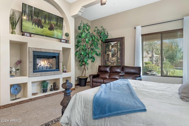 bedroom with a lit fireplace and carpet