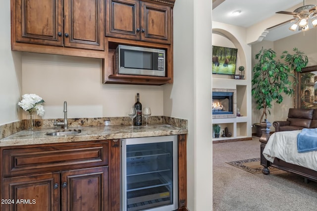 bar featuring carpet flooring, beverage cooler, indoor wet bar, stainless steel microwave, and a sink