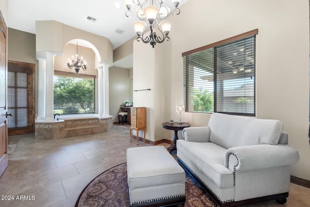living area with tile patterned flooring, visible vents, decorative columns, and a chandelier