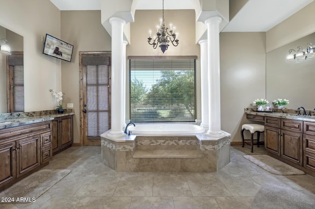 bathroom with a garden tub, decorative columns, two vanities, and an inviting chandelier