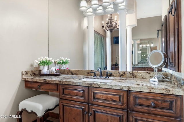 bathroom featuring decorative columns, an inviting chandelier, and vanity