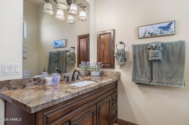bathroom featuring an inviting chandelier, vanity, and toilet