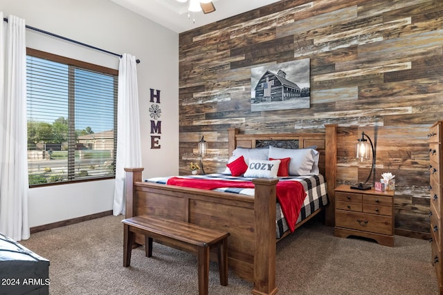 carpeted bedroom with baseboards, ceiling fan, an accent wall, and wooden walls