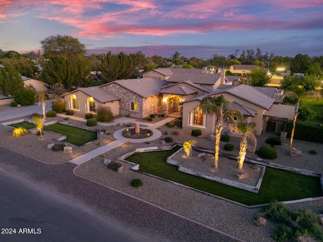 mediterranean / spanish house with a front yard, curved driveway, an outdoor fire pit, stone siding, and stucco siding