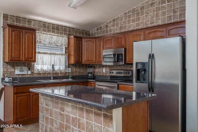 10618 W Pima St, Tolleson, AZ 85353 - kitchen featuring appliances with stainless steel finishes, brown cabinets, dark stone counters, a kitchen island, and lofted ceiling