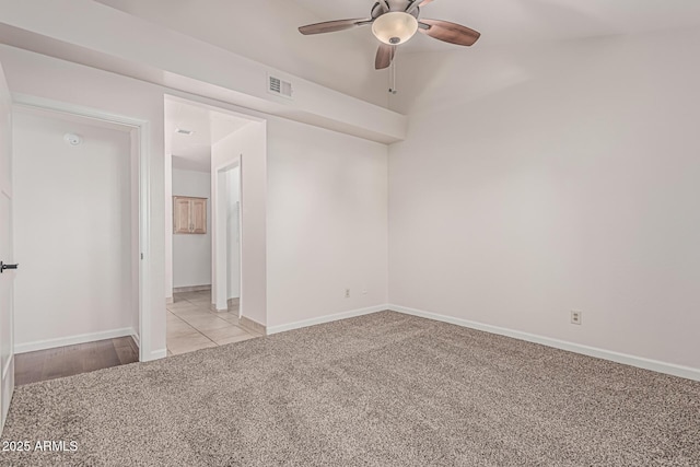 empty room with light colored carpet, visible vents, a ceiling fan, and baseboards